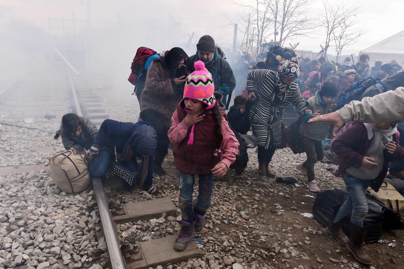 A child coughs as people run away after Macedonian police fired tear gas at hundreds of Iraqi and Syrian migrants who tried to break through the Greek border fence in Idomeni on Feb. 29.