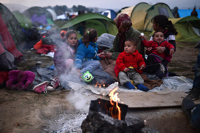 Refugees warm-up by a fire at a makeshift camp along the Greek-Macedonian border near the village of Idomeni on February 28, 2016. (AFP Photo)