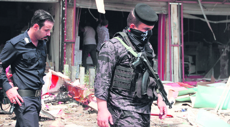 Two Iraqi police officers inspect damage after an explosion that killed more than 60 people.