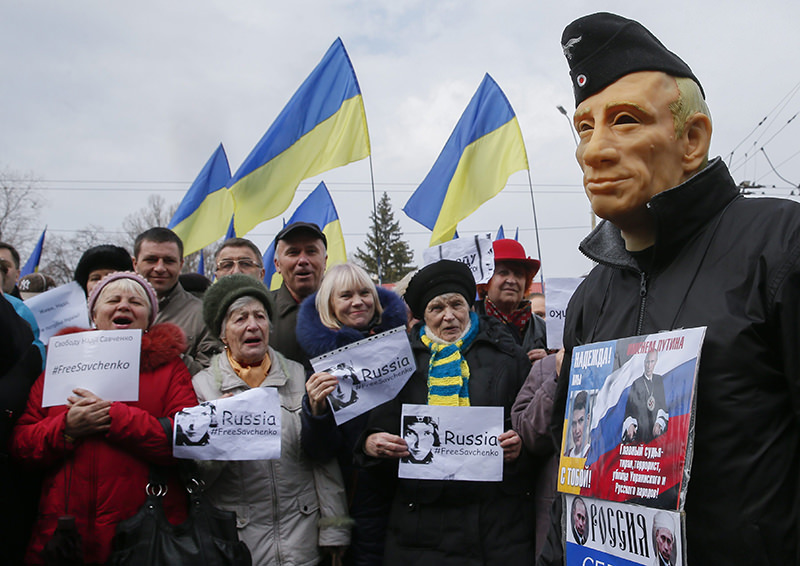 Protesters hold placards reading 'Free Savchenko' near a man wearing a mask depicting Putin during a rally in front of the Russian embassy in Kiev, Ukraine. (EPA Photo)