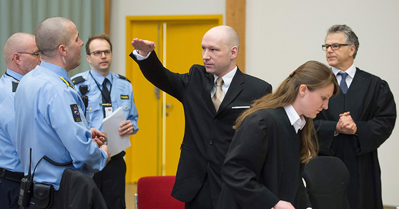Norwegian mass killer Anders Behring Breivik (C) makes a Nazi salute as he arrives to a makeshift court in Skien prisonu2019s gym on March 15, 2016 in Skien, some 130 km south west of Oslo (AFP Photo)