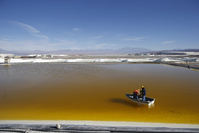 Workers use a boat to take samples from a brine pool at the Rockwood Lithium Plant on the Atacama salt flat, the largest lithium deposit currently in production, in the Atacama desert of northern Chile.