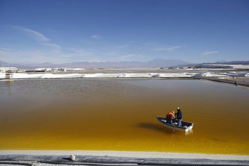 Workers use a boat to take samples from a brine pool at the Rockwood Lithium Plant on the Atacama salt flat, the largest lithium deposit currently in production, in the Atacama desert of northern Chile.