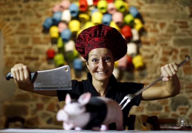 Italian chef Cristina Palanti poses with a meat cleaver and cooking fork hovering over a plastic pig figurine at the 'L'e'Maiala' restaurant in Florence on October 6, 2012. (REUTERS Photo)