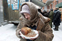 An elderly woman holds a plate of food she received at a distribution point for homeless in Moscow (Reuters Photo)