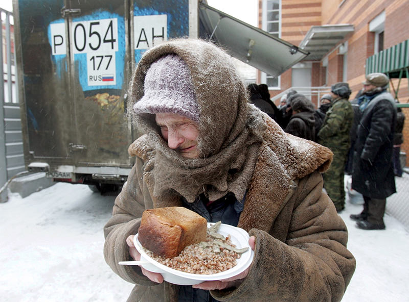 An elderly woman holds a plate of food she received at a distribution point for homeless in Moscow (Reuters Photo)
