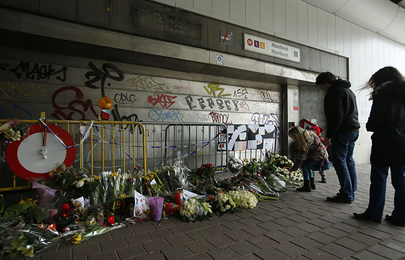 People stop, look at floral tributes placed outside the Maelbeek metro station, the scene of one of the bomb attacks on the Belgian capital, in Brussels, March 26, 2016 (AP)