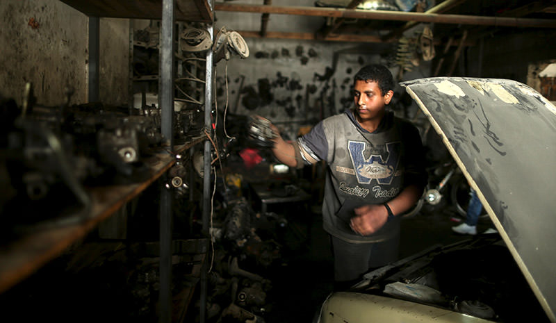 Palestinian boy Mohamoud Yazji, 16, who works as apprentice mechanic, repairs a car at a garage in Gaza City March 17, 2016. (Reuters Photo)