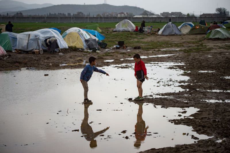 Two boys standing in a puddle at a makeshift camp for migrants and refugees at the Greek-Macedonian border near the village of Idomeni.