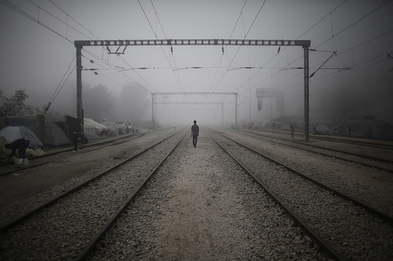 A refugee walks on the train tracks amidst morning mist at a refugee camp near the Greek-FYROM border near the village of Idomeni, northern Greece, 04 April 2016. (EPA Photo)