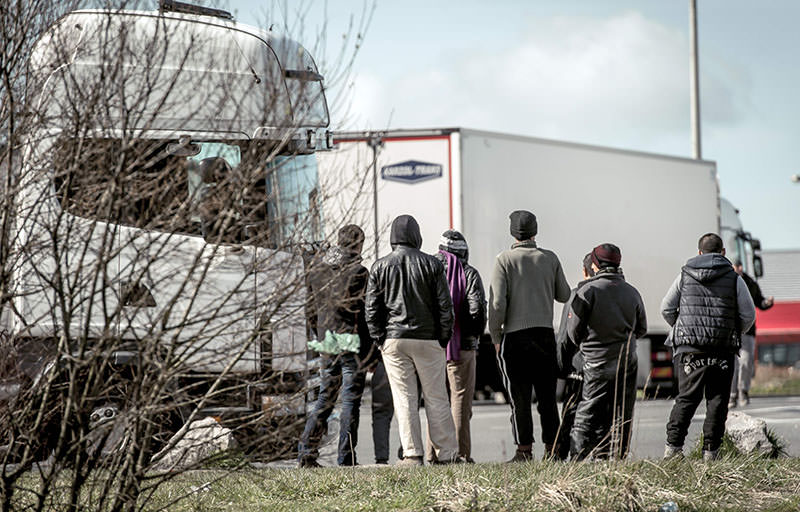 Refugees stand looking at lorries stationed in a parking lot in Marck, just north of the sea port of Calais on the English Channel on March 30, 2016 (AFP)