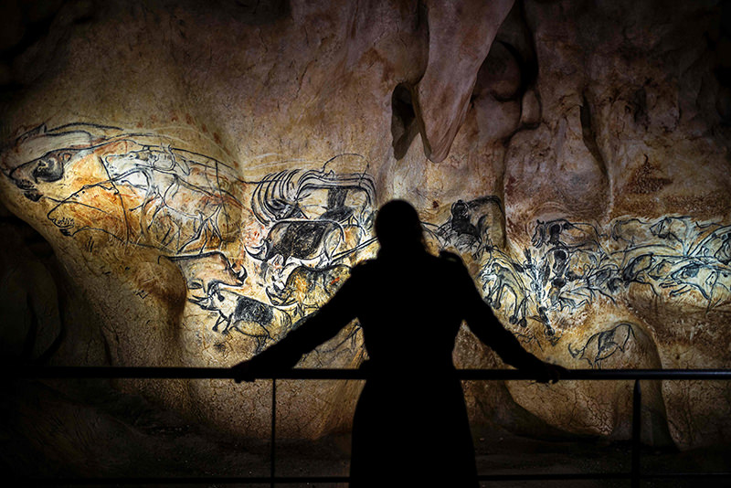 This file photo taken on April 8, 2015 shows a person looking at part of the full-scale reproduction of frescos found at the cave of Pont-D'Arc. (AFP Photo)