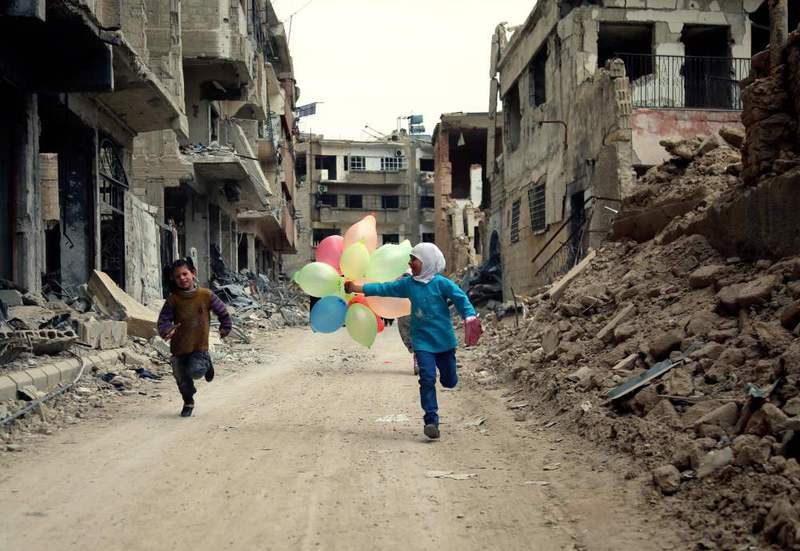 Syrian children with balloons running amid heavily damaged buildings in the neighbourhood of Jobar, on the eastern outskirts of the Syrian capital Damascus.