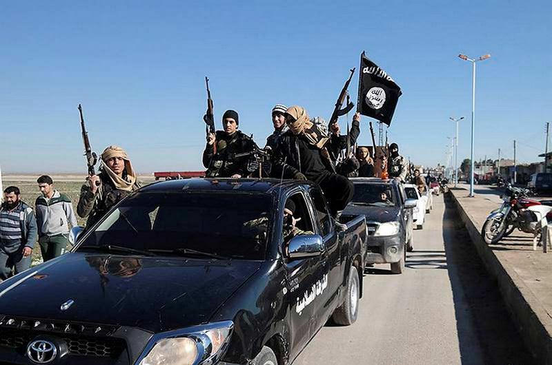 DAESH militants pass a convoy in Tel Abyad, northeast Syria.