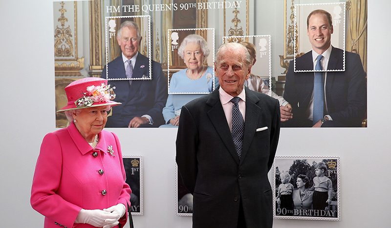 Britain's Queen Elizabeth II (L) and Britain's Prince Philip, Duke of Edinburgh pass a giant photograph taken to be used as part of a series of 10 Royal Mail postage stamps (AFP Photo)