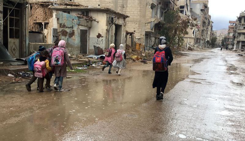 Syrian girls walk home from school in the rain in the southwestern city of Daraa, Syria.