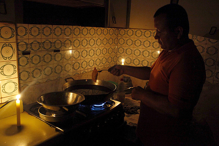 A man cooks lighted by candles lights at his home during a power cut in San Cristobal, in the state of Tachira, Venezuela, April 25, 2016 (Reuters Photo)