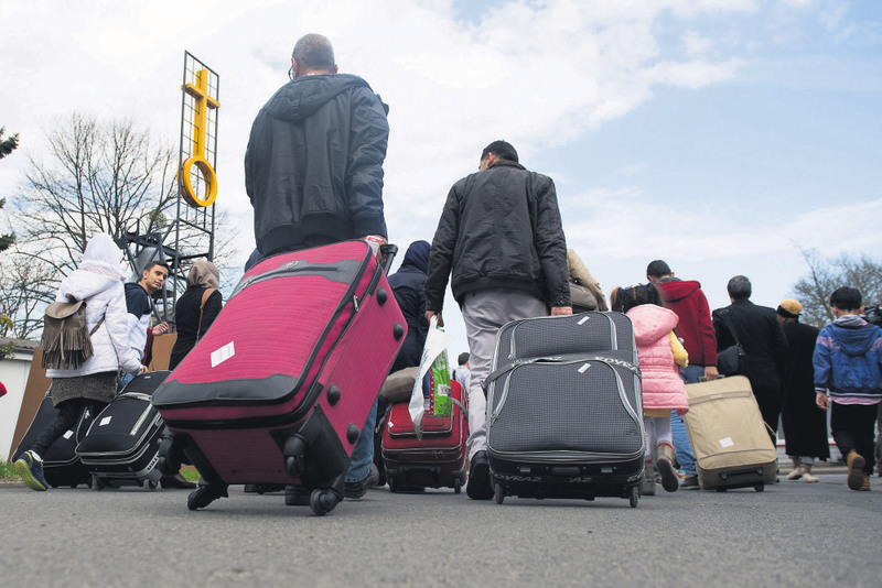 Syrian refugees haul their luggage near the Friedland border transit camp in Germany on April 4. Refugees were flown from Turkey in exchange for Turkey's admission of migrants from Greece.