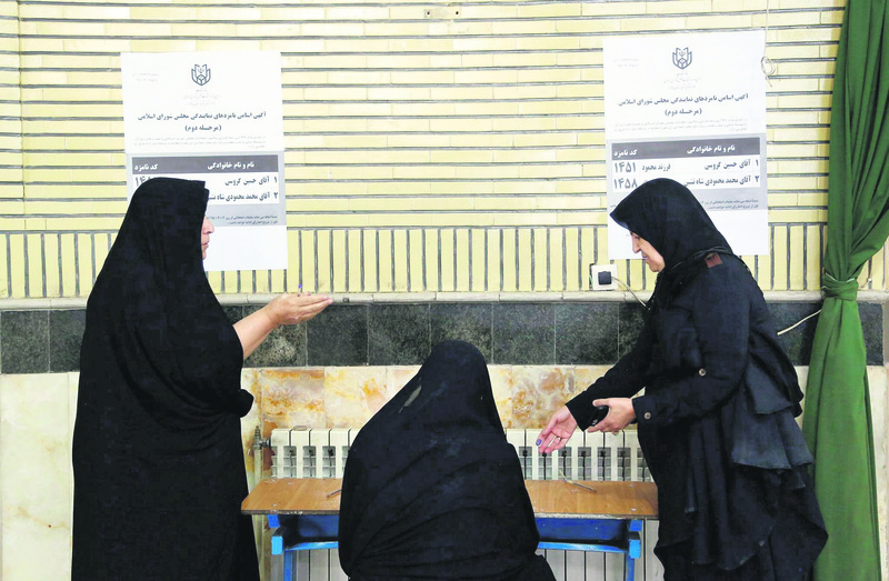Iranian women fill their ballot to vote in a polling station during the second round of parliamentary elections. (EPA Photo)