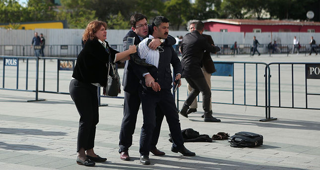 This picture released by Cumhuriyet daily shows Can Dündar in the background protected by another man, while his wife Dilek Dündar (L) trying to stop the gunman while CHP Deputy Muharrem Erkek from behind to prevent further shots. (AFP Photo)