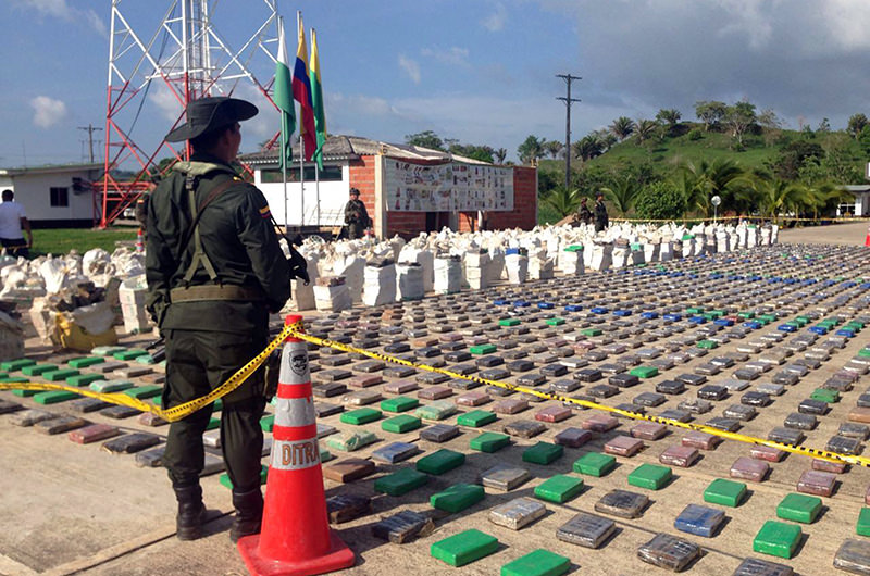 A Colombian national policeman stands guard in front of packages of cocaine, which were confiscated in Turbo province near the border with Panama, May 15, 2016 (Reuters Photo)