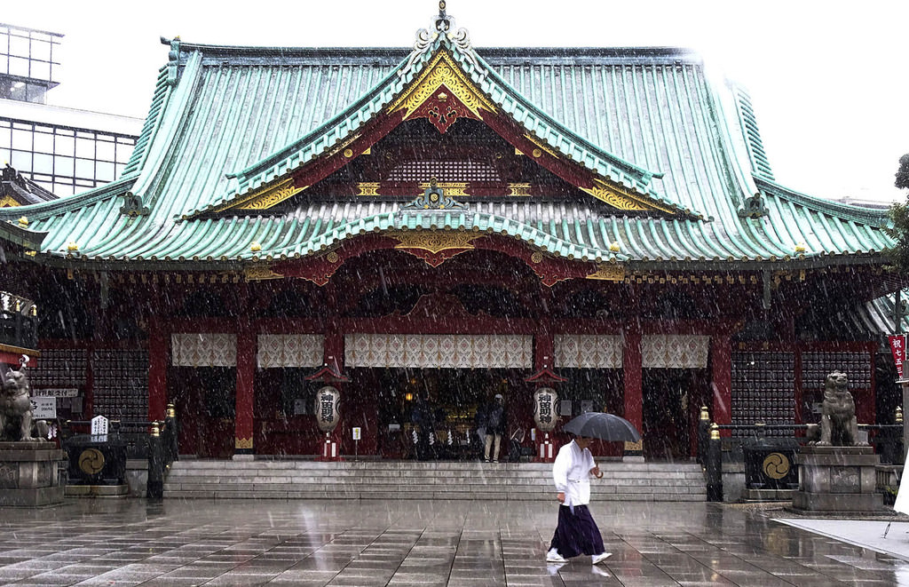 A shrine staff walks in the snow at Kanda Myojin shrine in Tokyo, Thursday, Nov. 24, 2016 (AP Photo)