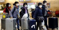 Tourists from Korea wearing protective masks walking with their belongings while waiting for a flight back to South Korea at the Ben Gurion airport near Tel Aviv, Israel, Monday, Feb. 24, 2020. (AP Photo)