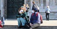 People wearing a respiratory mask sit on the steps of the churchyard of the Cathedral of the Duomo of Milan, Feb. 24, 2020. (AFP Photo)