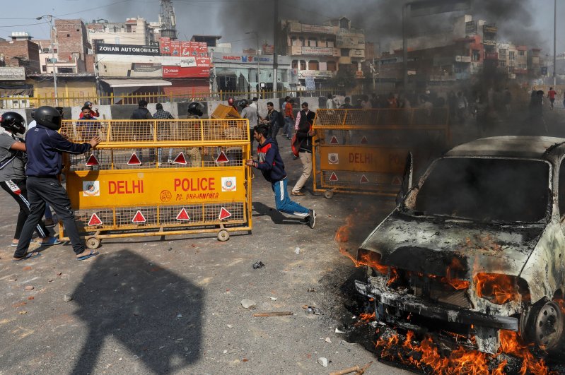 People supporting a new citizenship law push police barricades during a clash with those opposing the law, New Delhi, Feb. 24, 2020. (Reuters Photo)