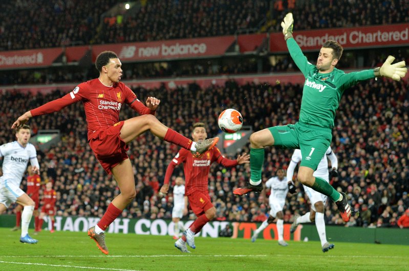 Trent Alexander-Arnold (L) of Liverpool beats West Ham goalkeeper Lukasz Fabianski to give the assist, Liverpool, Feb. 24, 2020. (EPA Photo) 