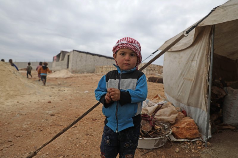 A displaced Syrian boy stands outside a tent at an informal camp in Kafr Lusin village on the border with Turkey in Syria's northwestern province of Idlib, Feb. 21, 2020. (AFP Photo)