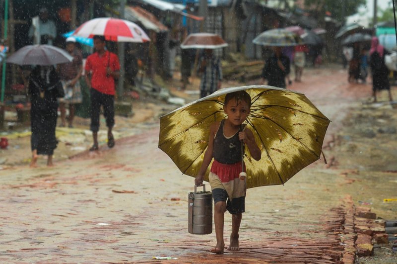 A Rohingya refugee boy shelters under an umbrella as he makes his way during a monsoon rainfall at Kutupalong refugee camp, Ukhia, Sept.12, 2019. (AFP Photo)