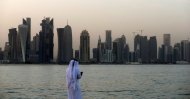 A man looks at his phone on the corniche of the Qatari capital Doha, July 2, 2019. (AFP Photo)