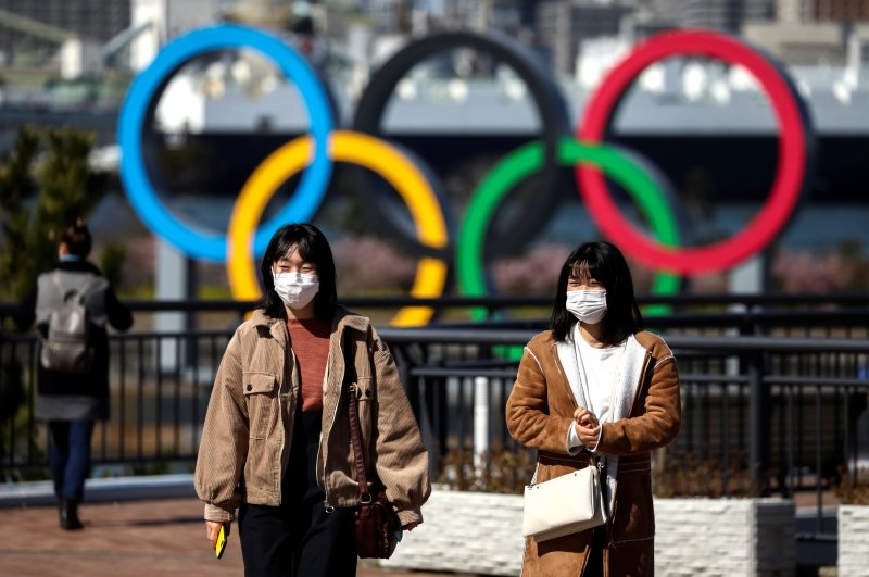 People wearing protective face masks are seen in front of the Giant Olympic rings at the waterfront area at Odaiba Marine Park, Tokyo, Feb. 27, 2020. (REUTERS Photo)