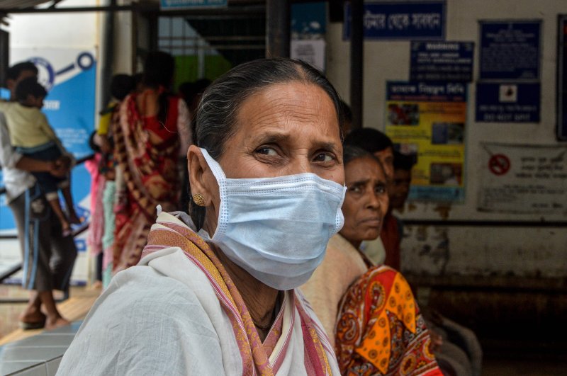 An elderly woman wearing a protective facemask sits with other patients at the Siliguri District Government hospital, Siliguri, Feb. 21, 2020. (AFP Photo)