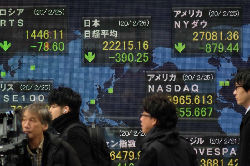 Pedestrians walk past an electronic quotation board displaying share prices of the Nikkei 225 Index (C, top) and other global stock markets in Tokyo, Feb. 26, 2020. (AFP Photo)