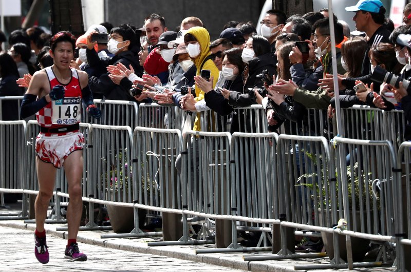 Spectators in face masks watch as a runner participates at the Tokyo Marathon 2020, Tokyo, Mar. 1, 2020. (Reuters Photo)