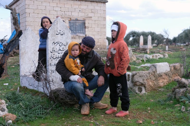 Ebu Yusuf, alongside with his three children and wife, took refuge at a cemetary near Turkish border, escaping from Syrian regime assaults, March 1, 2020. (DHA)