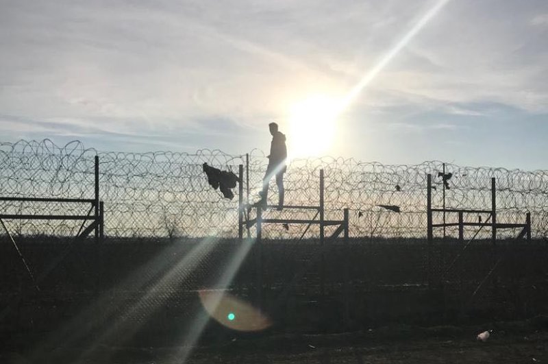 This photo shows a migrant crossing the Turkish-Greek border over a fence