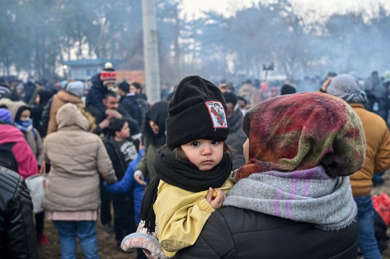 A child looks on as migrants wait to pass the buffer zone at Turkey-Greece border, at Pazarkule, in Edirne district, on February 29, 2020. (AFP Photo) 