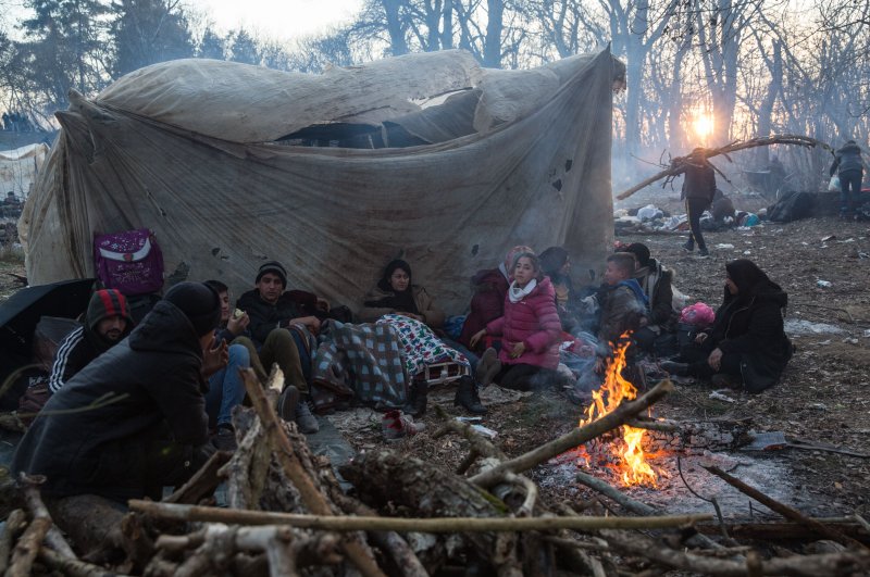 Migrants stuck on the Turkey-Greece border light a fire to warm up as they wait to cross into Greece in Edirne, Sunday, March 1, 2020 (DHA Photo)