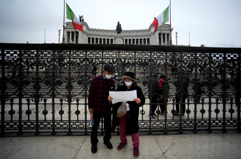 Tourists wearing protective masks stand in front of the Vittoriano in central Rome, March 1, 2020. (AFP Photo)