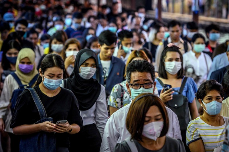 Commuters wearing facemasks wait for a canal boat, Bangkok, March 2, 2020. (AFP Photo)