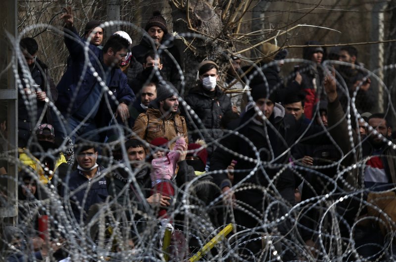 Migrants stand behind a fence near the Kastanies border gate at the Greek-Turkish border, March 1, 2020.. (AP)
