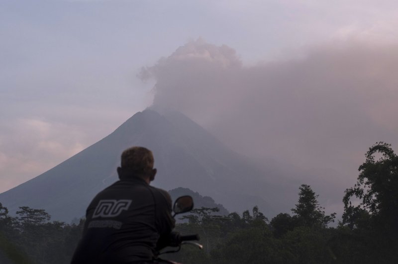 A man watches as Mount Merapi spews volcanic material into the air in Sleman, Indonesia, Tuesday, March 3, 2020. (AP Photo)