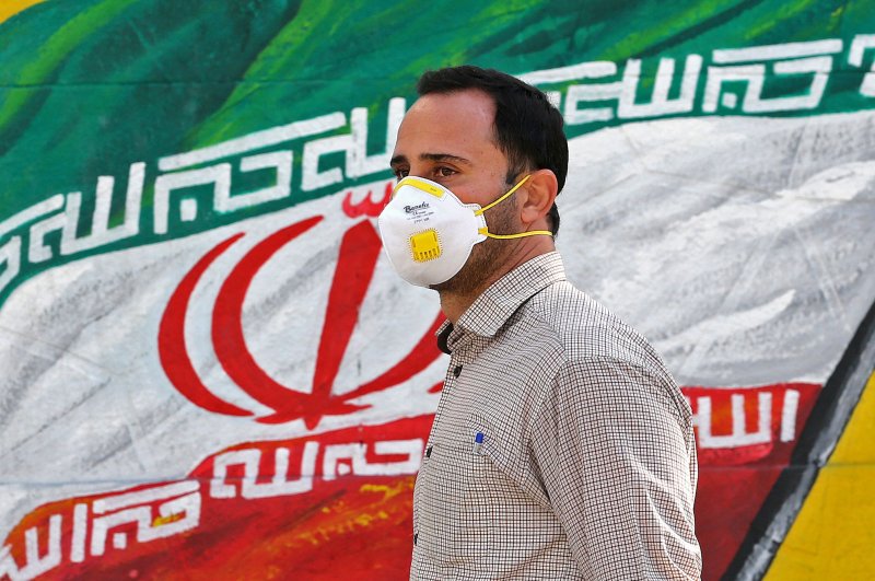 Man wearing a face mask walks past a mural of Iran's national flag in Tehran, Iran, March 4, 2020. (AFP Photo)