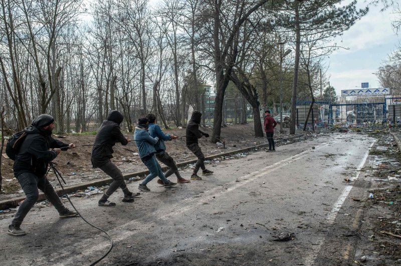 Migrants try to remove fences during the clashes with Greek police, after they tried to pass on the Greek side, on the buffer zone near Pazarkule crossing gate in Edirne, Turkey, on March 4, 2020. (AFP Photo)