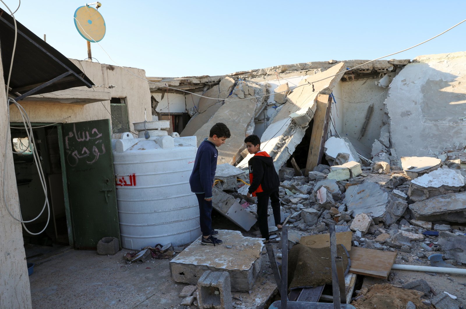 Boys stand near a damaged house after Haftar forces' shelling on a residential area, in Abu Slim district south of Tripoli, Libya February 28, 2020.  (REUTERS Photo)