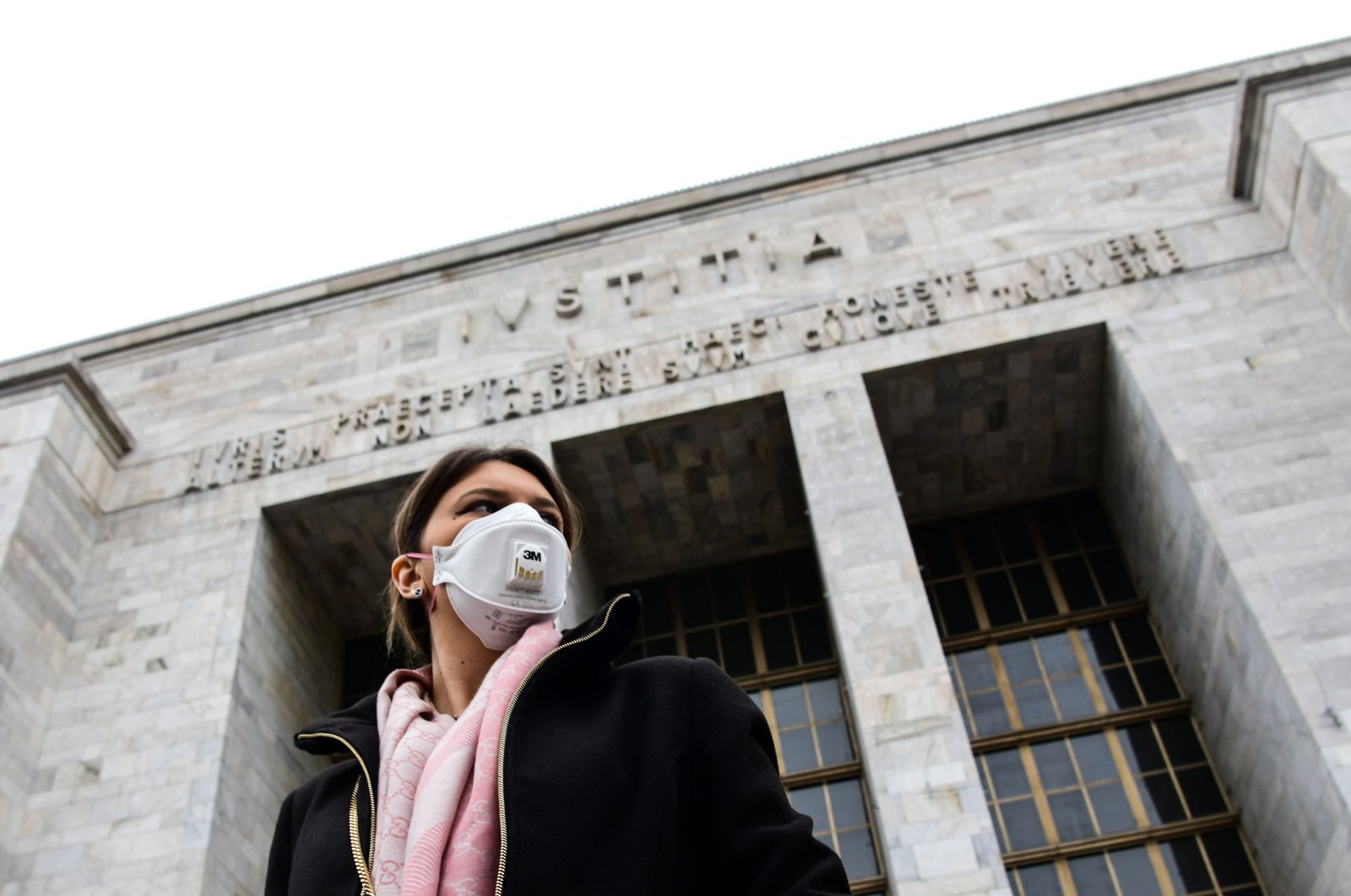 A woman wearing a respiratory mask exits from the Palace of Justice in Milan, on March 5, 2020. (AFP Photo)