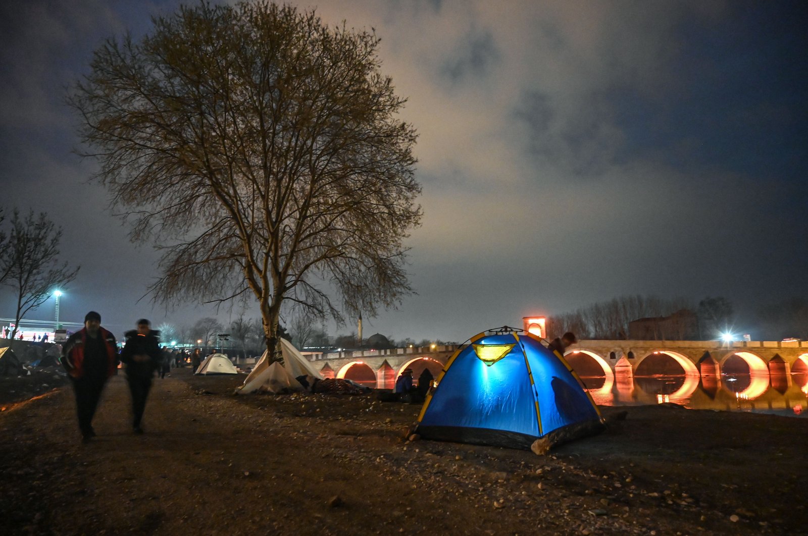 Migrants spend the night in a makeshift camp on the bank of the Tunca river as they try to enter Europe at the Turkey-Greece border, near the Pazarkule crossing gate in Edirne, March 5, 2020. (AFP Photo)